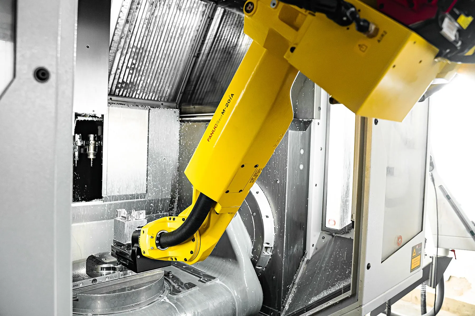 Automatisert CNC-produksjon hos Radoxx Gul robotarm ved en CNC-maskin i produksjonsanlegget til Radoxx Components